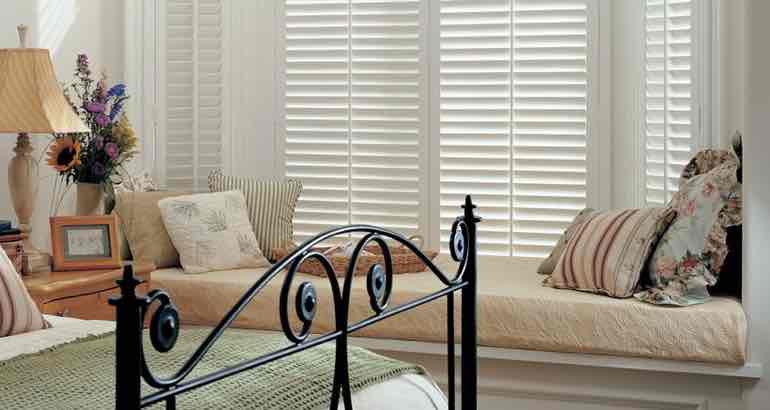 Polywood shutters in a white bedroom bay window.